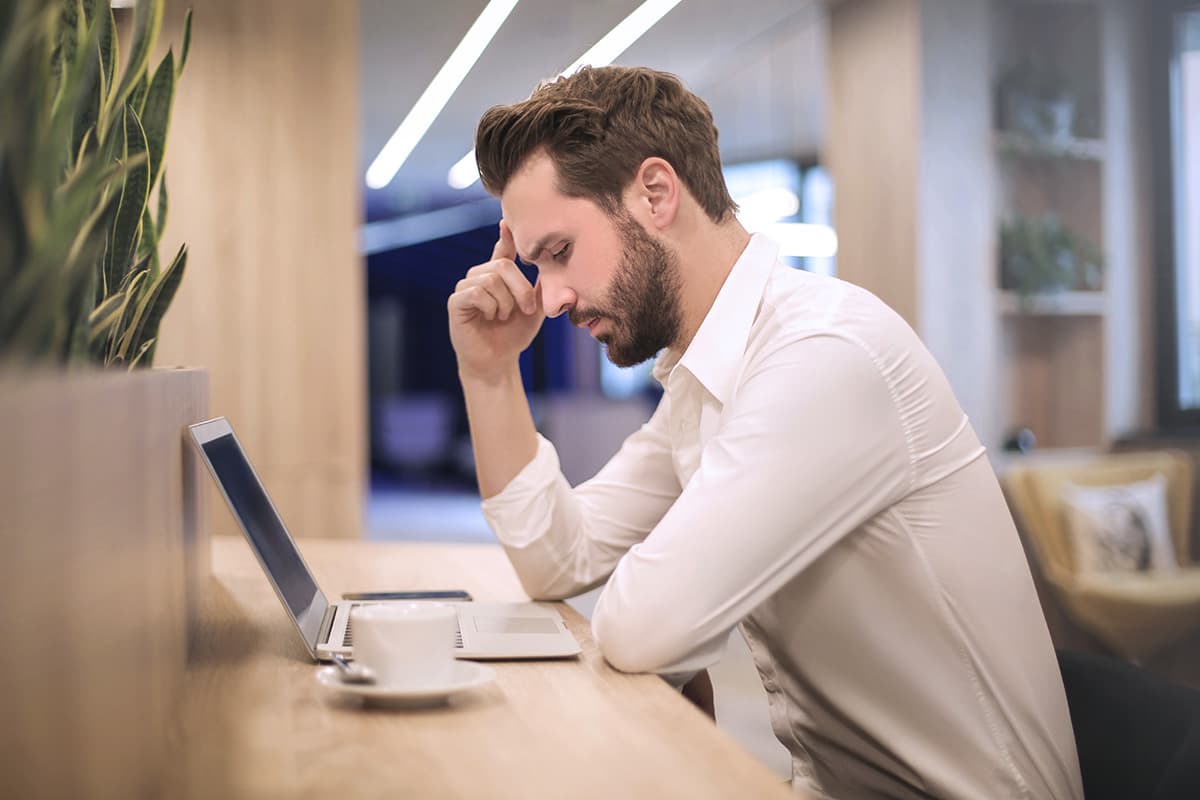 Serious man sitting by desk with laptop.