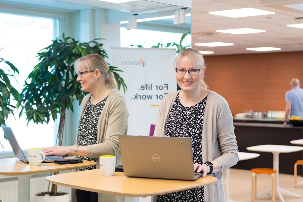 Blond woman working with laptop in office environment. 