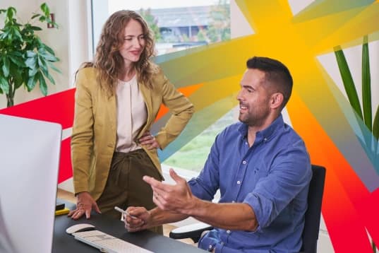 Nainen ja mies keskustelevat työpöydän ääressä