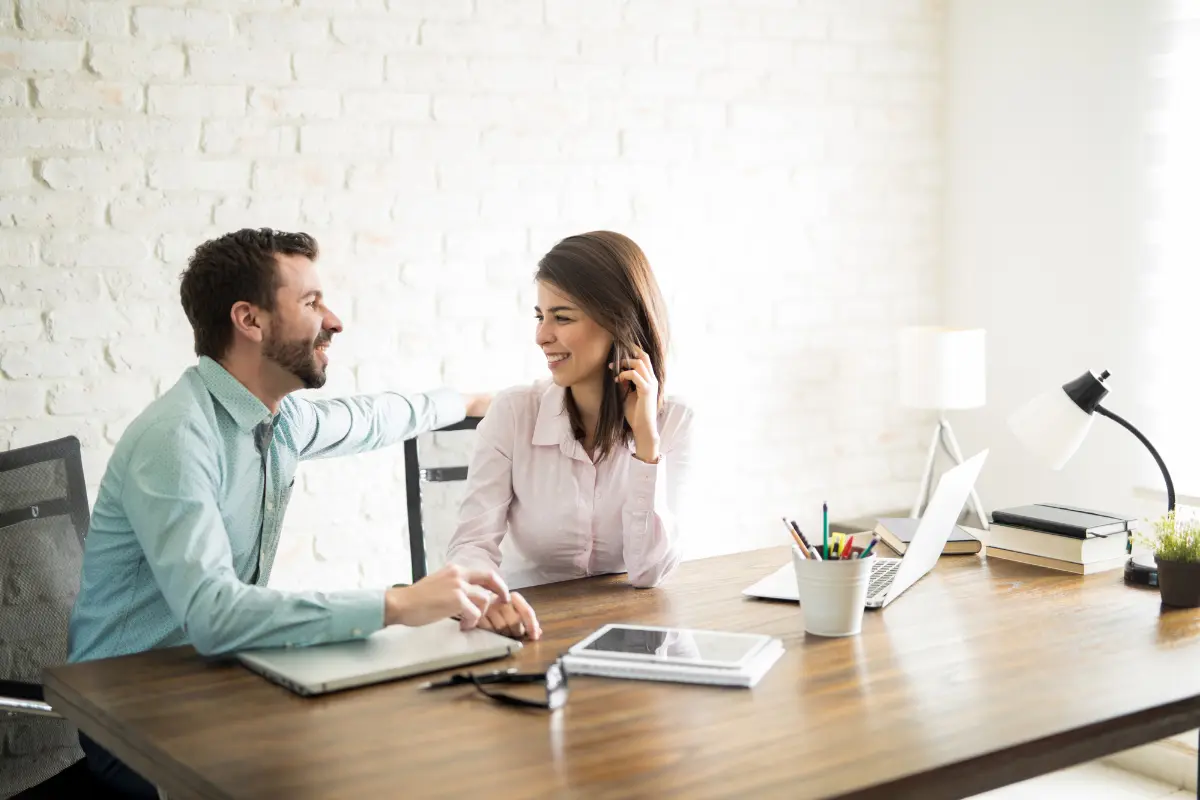 Nainen ja mies istuvat käsi kädessä työpöydän ääressä